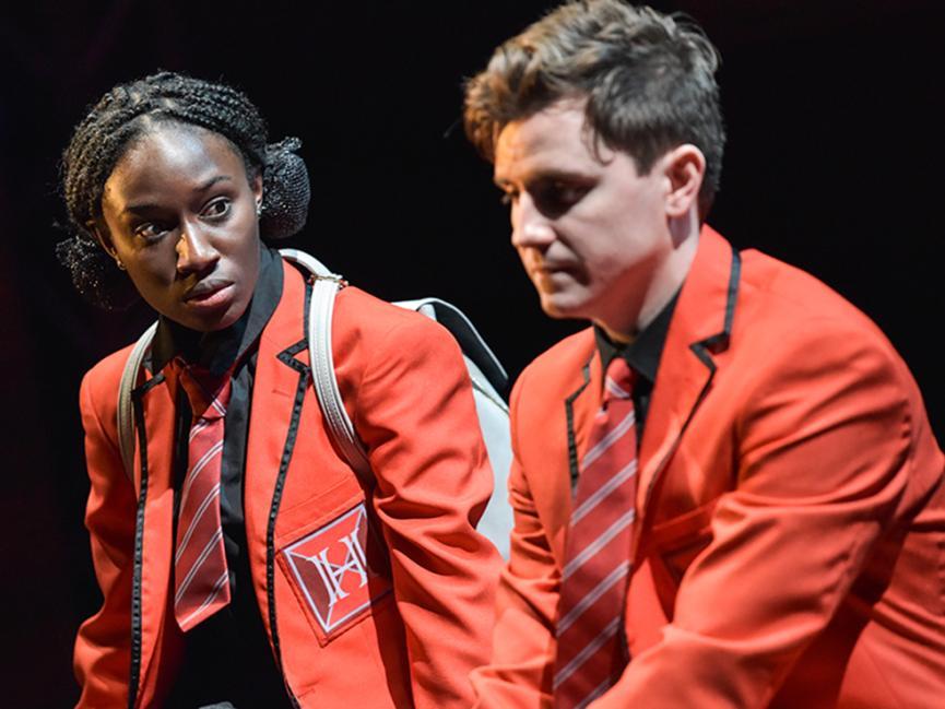 Two students sit in blazers on stage