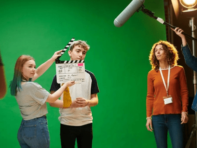 Two workshop participants standing in front of a green screen once with a movie clipboard