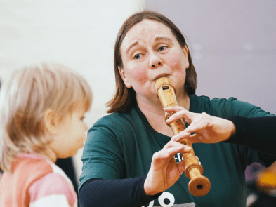 A performer playing the flute to a toddler