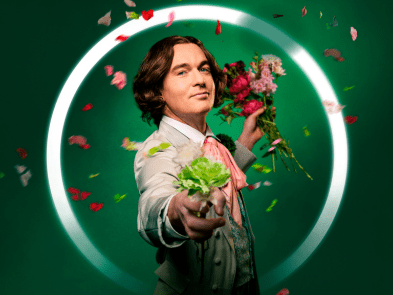 A man against a green background with flowers floating around him