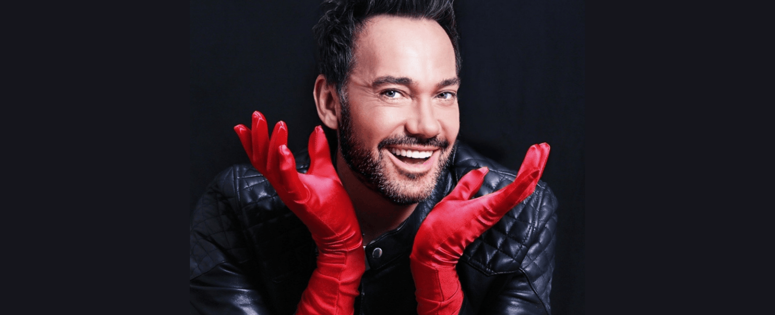 Craig Revel Horwood smiling with red gloves