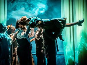 Perfromer is carried by one group while sticking on leg up in front of beautiful green background