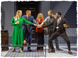 Actors in suits and smart clothes putting their hands into the middle of where they are all stood