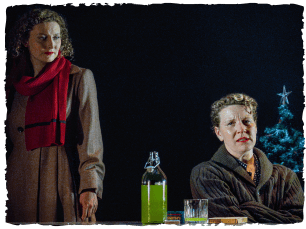 Woman sat down at table, woman stood behind her