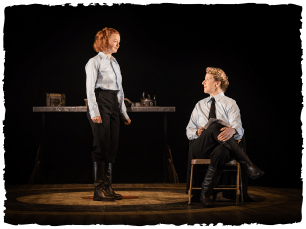 Two actors on stage, on sitting down one standing