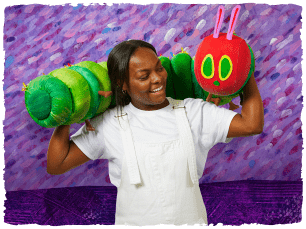 A Performer lifts a puppet of the very hungry caterpillar
