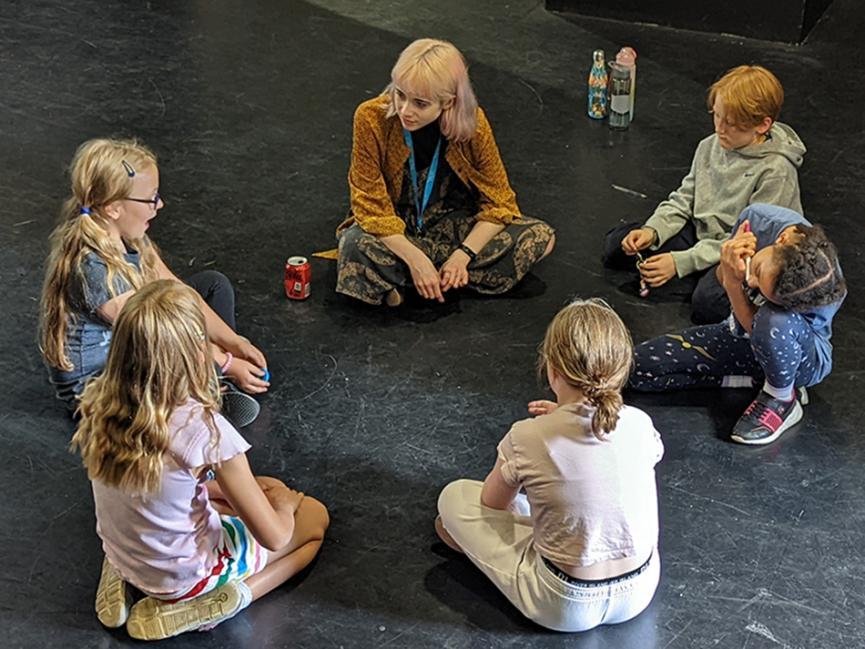 A group of children sit in a workshop