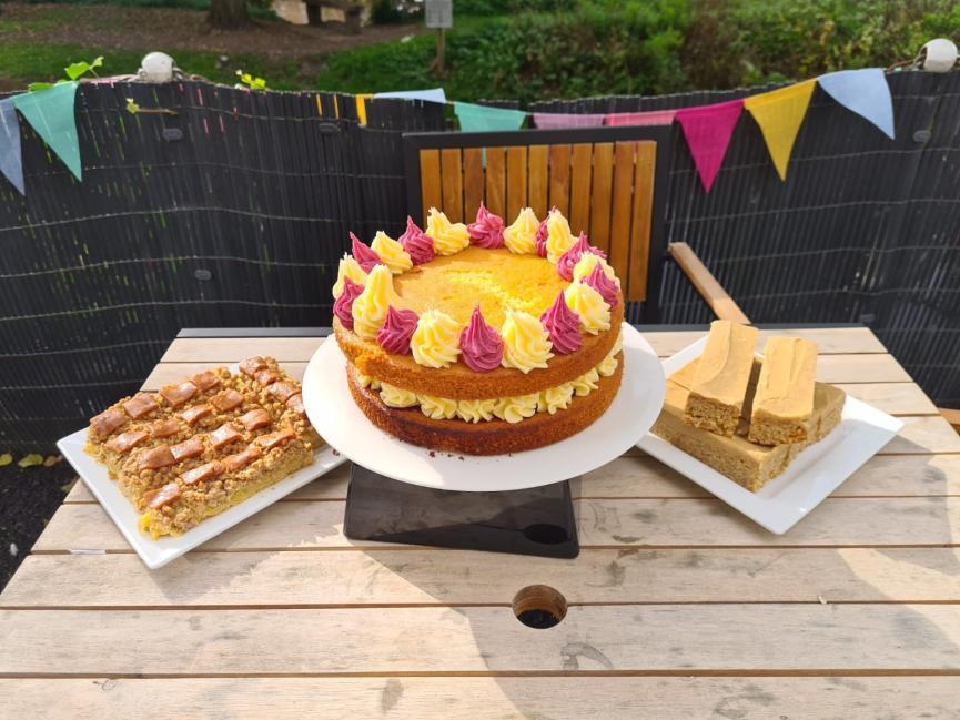 Three plates of various cakes on a table, with bunting behind
