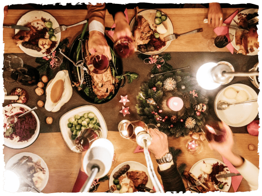 A Spread of plates on a wooden table with elements of a of a christmas dinner and drinks