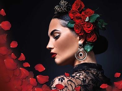 A performer with red roses in her hair looking to the right of frame