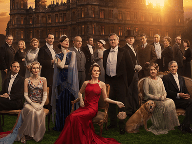 Photo of the downton abbey cast dressed in black tie against a background of the house