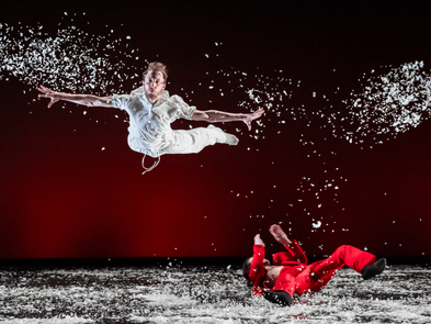 Man in white flying through the air with confetti, with someone in red on the floor