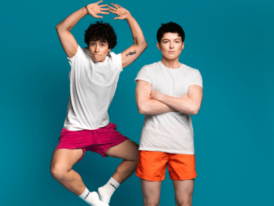 2 people, one serious with arms crossed, one jumping in air. 