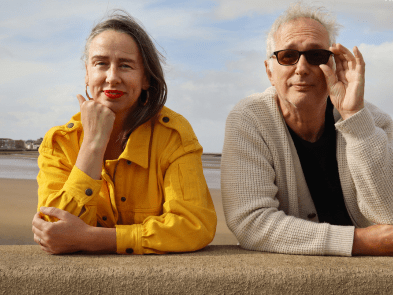 Henry Normal with glasses on and Jan. Blue skies and cloudy background