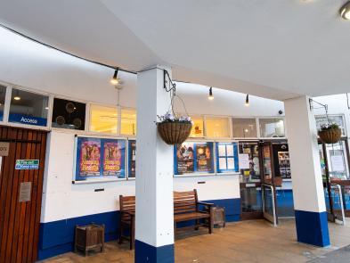 Outside the front of the venue. A brown access door is shown on the left.